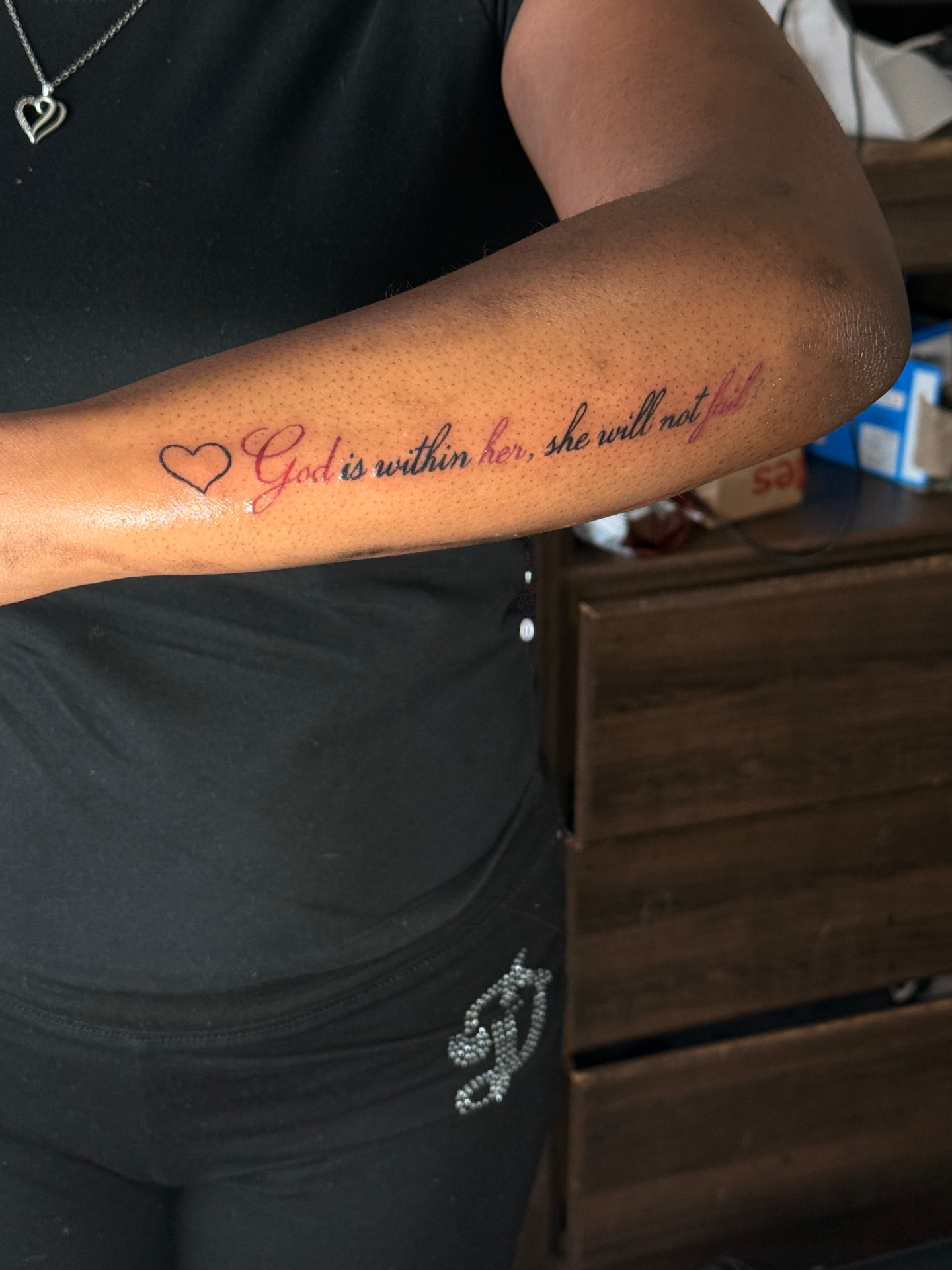 God is within her script forearm tattoo with red accents